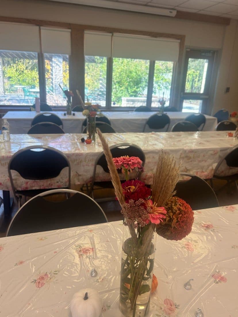 Zinnia, dahlia, and dried grass centerpieces on floral tablecloths at a Toledo fall event